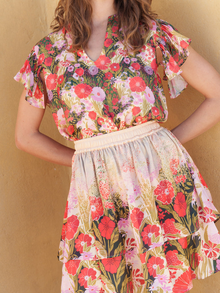 Red floral top with beige skirt.