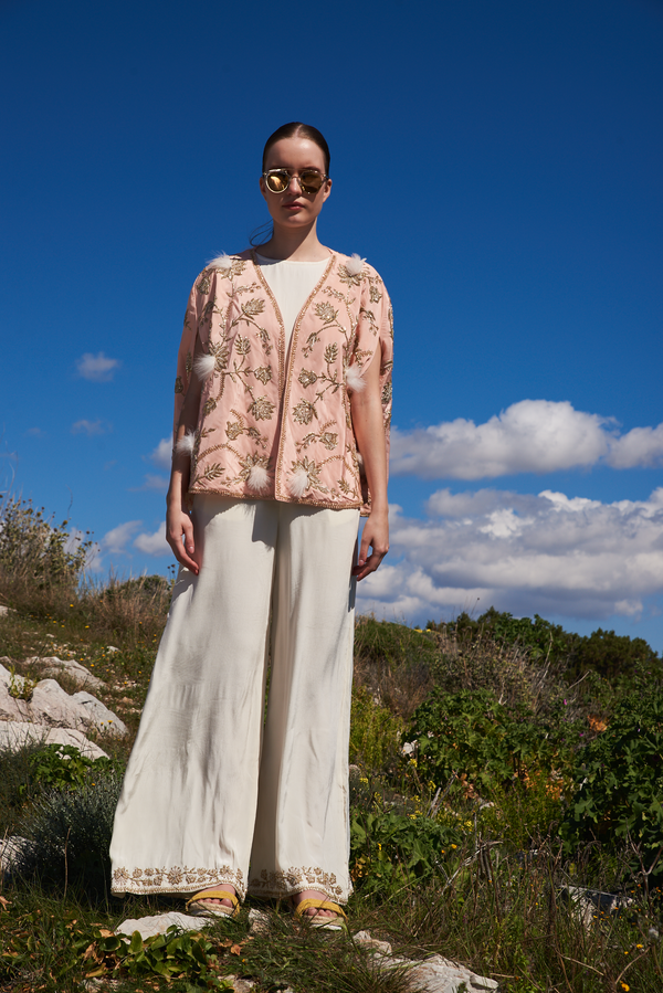 Salmon embroidered cape with feathers and white jumpsuit with embroidery at hem